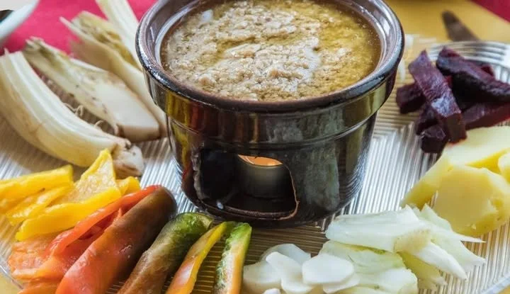 Piatto di Bagna Cauda con verdure fresche in un contesto conviviale.